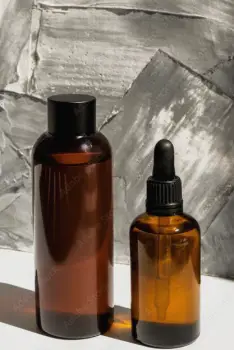 Glass of alcohol on a table beside two closed medicine bottles