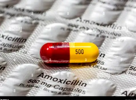 White and orange amoxicillin capsules resting on a surface