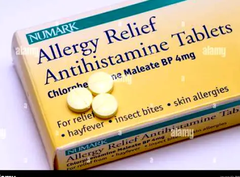 Antihistamine tablets visible inside a white plastic bottle on a countertop