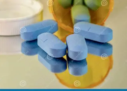 Close-up of a prescription bottle labeled with antiviral medication next to a glass of water