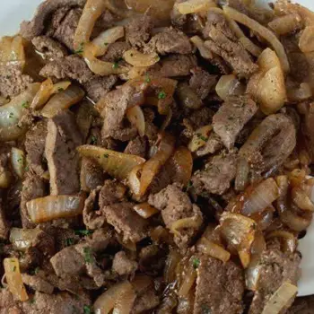 Close-up of a cooked slice of beef liver on a white plate