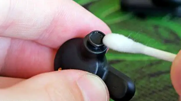 Hands wiping down a reusable earbud with a soft cloth