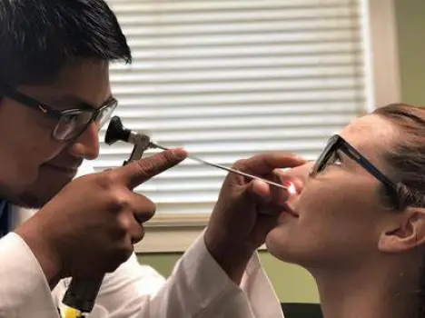 Clinician examining a patient's nasal passages during an office visit