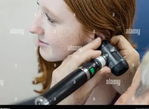Clinician using an otoscope to examine a patient's ear canal and eardrum