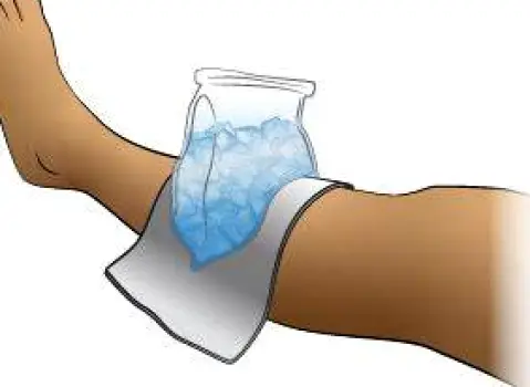 A hand pressing a cloth-wrapped cold pack against a small red area on a limb