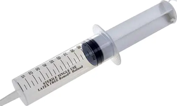 A measuring dose syringe beside a small baby toy ball