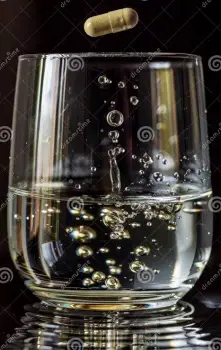 Single doxycycline capsule resting on a table next to a full glass of water ready for ingestion