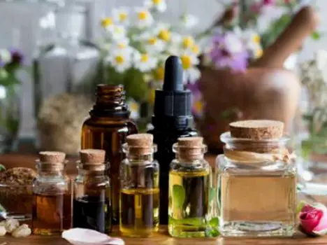 Small amber essential oil bottles next to a larger bottle of carrier oil on a wooden surface