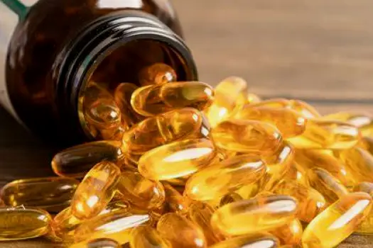 Fish oil capsules placed beside a cooked salmon fillet