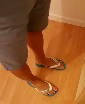 Flip-flops worn on a wet locker room floor, protecting feet from direct contact with a communal surface