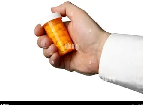 Person holding a pill bottle in one hand and examining a red skin patch on their other arm