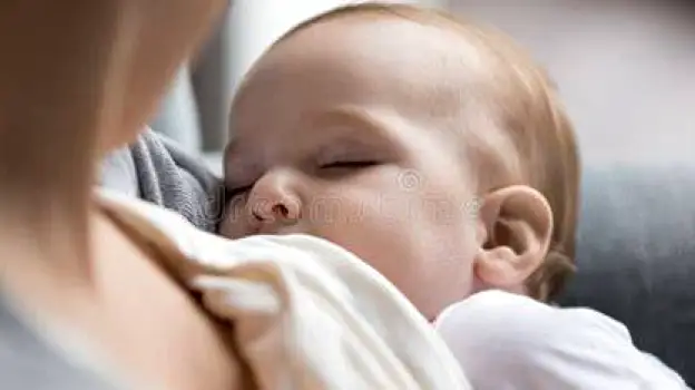 Mother cradling a drowsy, fussy breastfed infant in her arms at home