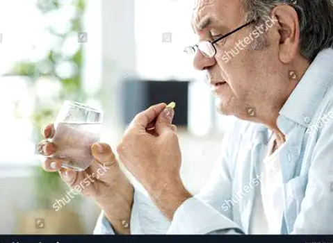 Person swallowing an antibiotic capsule with a glass of water at home