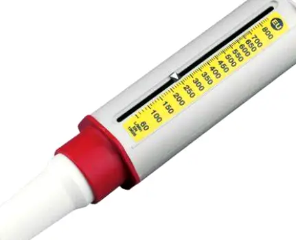 Person standing next to a peak flow meter, holding the device to measure lung function