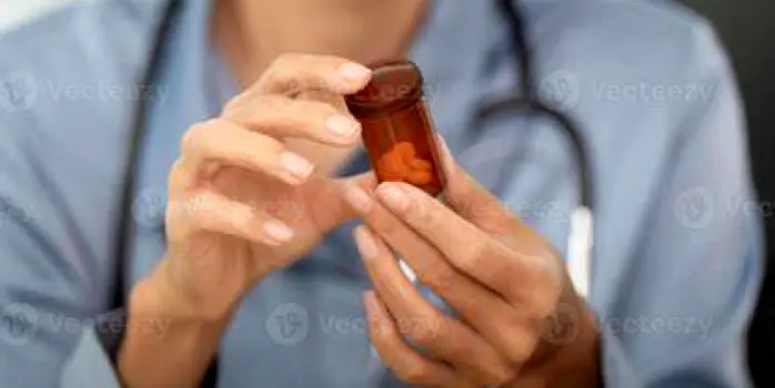 Close-up of a person's hands holding an over-the-counter medication bottle and turning it to examine the printed label, illustrating the step of checking the active ingredient panel before combining medicines.