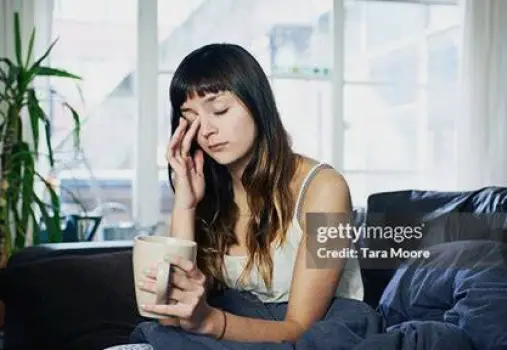 Person resting on a sofa with eyes closed, appearing drowsy