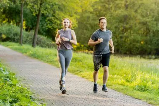 Person walking briskly along a tree-lined path as a low-impact aerobic activity