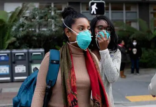 Person wearing a face mask in a public setting to prevent spreading the virus after symptoms improve