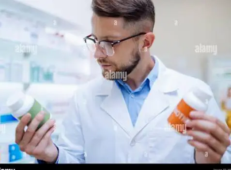 A pharmacist holding a generic cetirizine bottle and pointing to the label while speaking to a customer