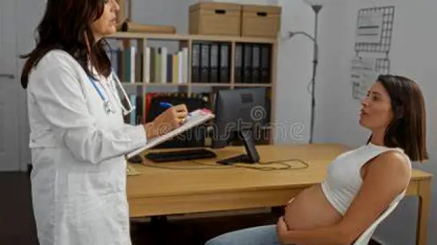 Pregnant woman discussing medication with a healthcare professional in a clinic office