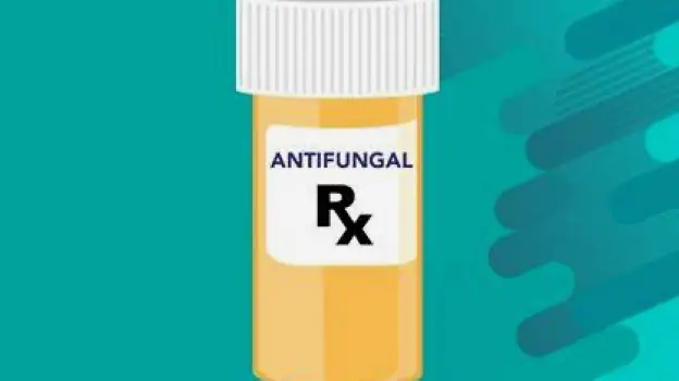 Prescription antifungal pills in a pharmacy container next to a topical medication tube