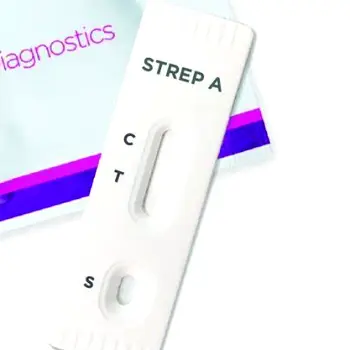 A rapid strep test swab and a test cassette placed on a clean surface