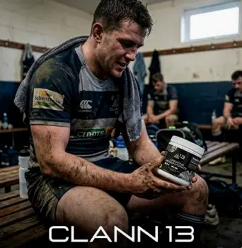 Male rugby player in team uniform holding a plastic container of creatine powder