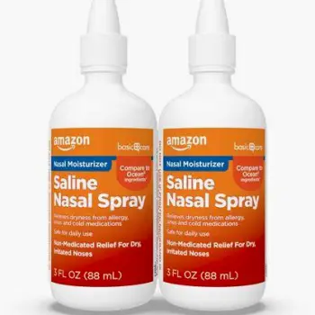 Bottle of saline nasal spray next to a neti pot for nasal irrigation