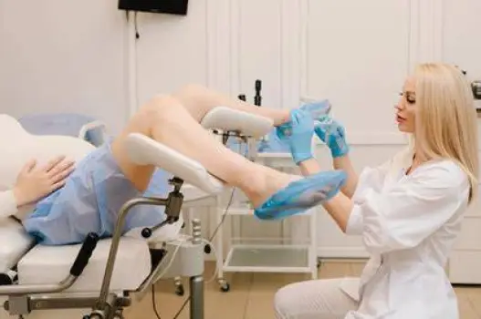 Healthcare professional in gloves preparing a vaginal swab sample in a clinic examination room