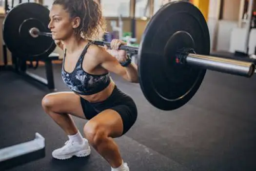 Woman performing a heavy barbell squat in a gym setting illustrating resistance training supported by creatine supplementation